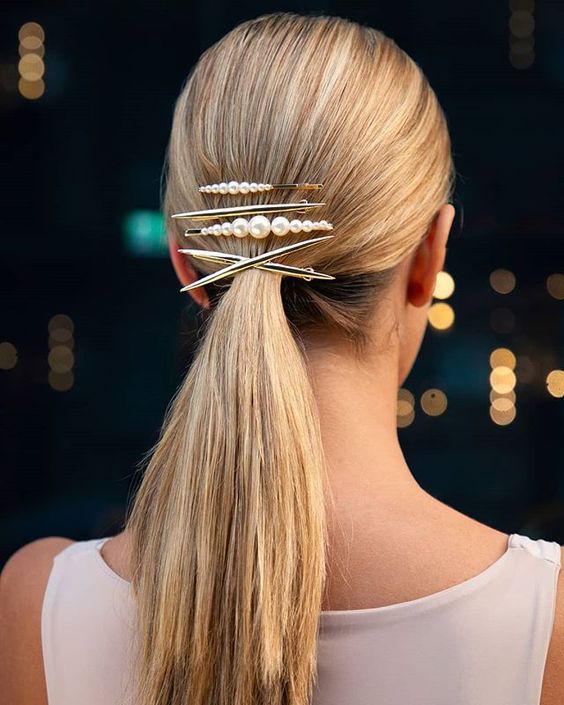 a sleek low ponytail secured with several bobby pins and a barrette for a modern look