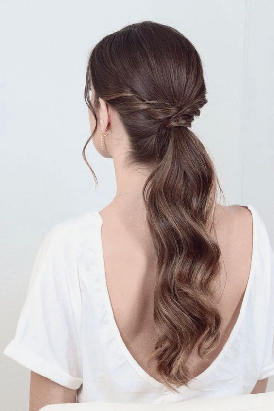 A stylish low ponytail with twists and a sleek top, with waves and face framing hair is a cool and catchy idea