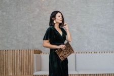 a stylish winter wedding guest look with a dark green velvet midi dress, brown shoes, a leopard clutch and statement earrings