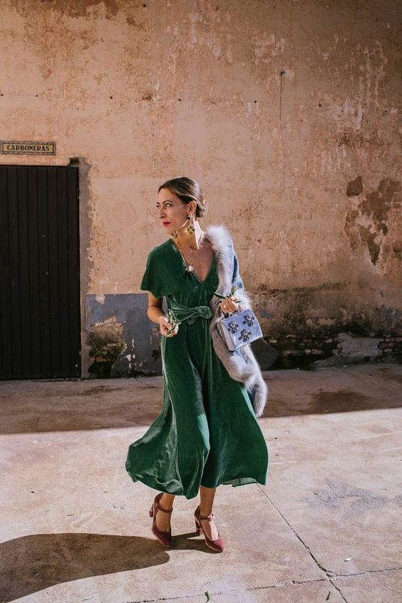 beautiful and chic winter wedding guest look with a green velvet midi dress, mauve velvet shoes, a blue velvet bag and faux fur