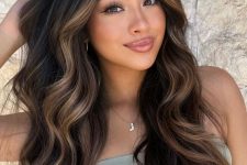 long and volumetric dark brown, almost black, hair with caramel to golden blodne balayage and waves is a gorgeous idea