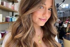 long and volumetric light brown hair with golden blonde balayage and waves is a gorgeous idea to look amazing