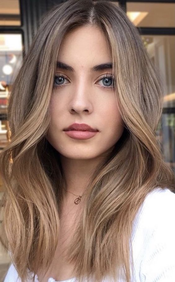 long light brown hair of a cold shade, with caramel balayage and face-framing highlights is chic