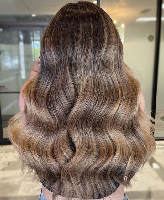 long volumetric light brown hair with darker root and waves is a fantastic idea to rock right now