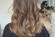 medium-length light brown hair with blonde highlights, waves and volume is a stylish and chic idea