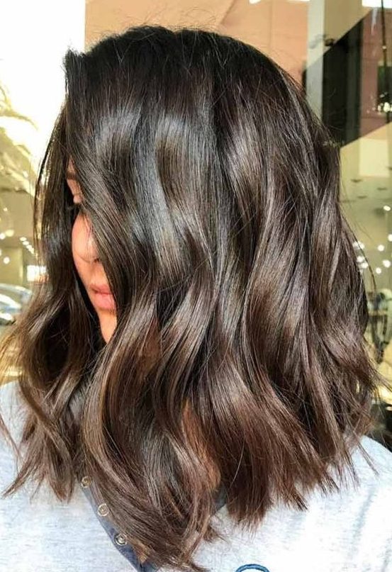 A beautiful and luxurious dark brunette medium length wavy haircut with highlights is a lovely idea