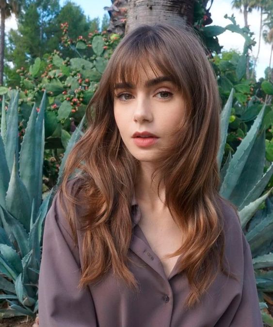 Lilly Collins wearing a long butterfly haircut finished off wiht Birkin bangs looks very cute