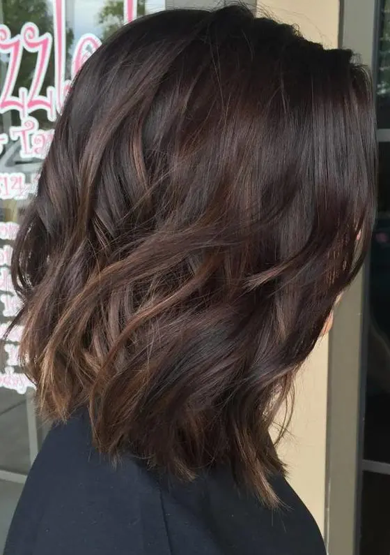 dark chocolate wavy hair with subtle caramel balayage to make the look more eye-catchy