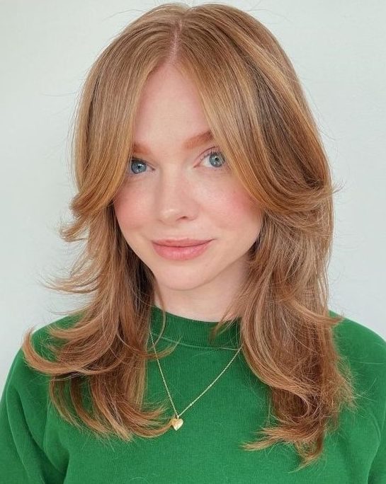 a ginger medium butterfly haircut with long curtain bangs and curled ends is a lovely solution