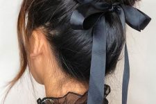 a beautiful messy top knot with a volume on top and a black ribbon bow is a cool and feminine hairstyle for Christmas