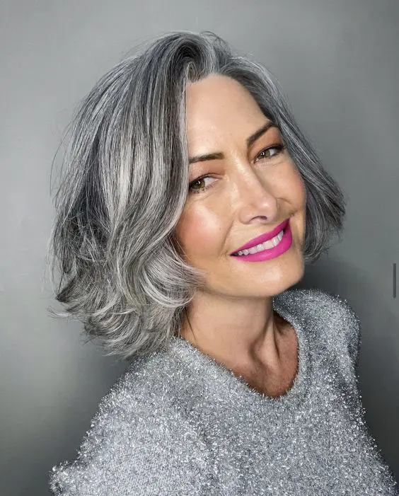 a beautiful midi bob in brown with a lot of silver grey balayage blending naturally with grey hair, with curled ends, is a chic hairstyle