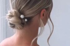 a beautiful woven twisted low bun with pearl hair pins and waves down is a lovely and modern solution for many occasions