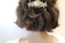 a catchy half updo with a wavy top and waves down plus a lovely coastal hair piece