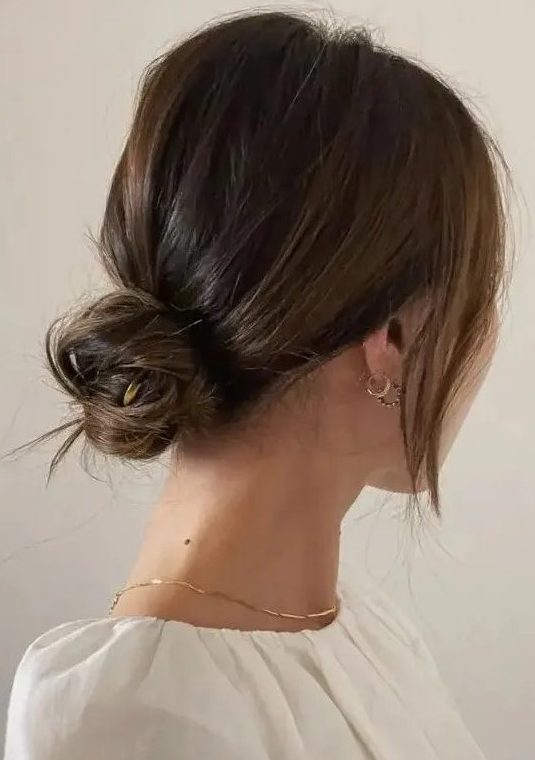 a chic and cool messy low bun with a bump on top and face-framing locks is a cool hairstyle for medium hair