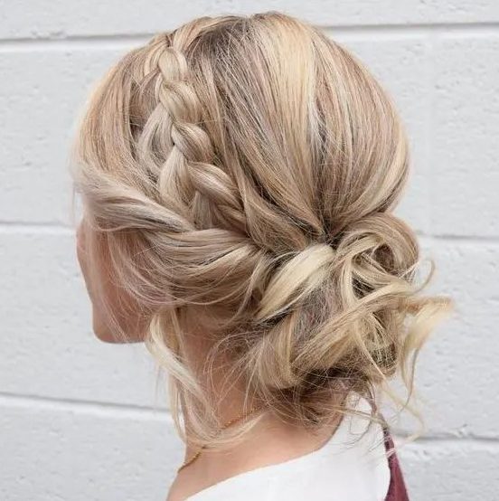 a cool messy and curly low updo with a braided halo and some locks and curls down for an effortlessly chic look