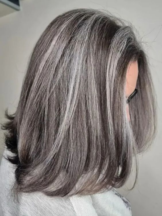 a dark long bob with grey highlights and curled ends, with a lot of volume, is a chic and catchy solution