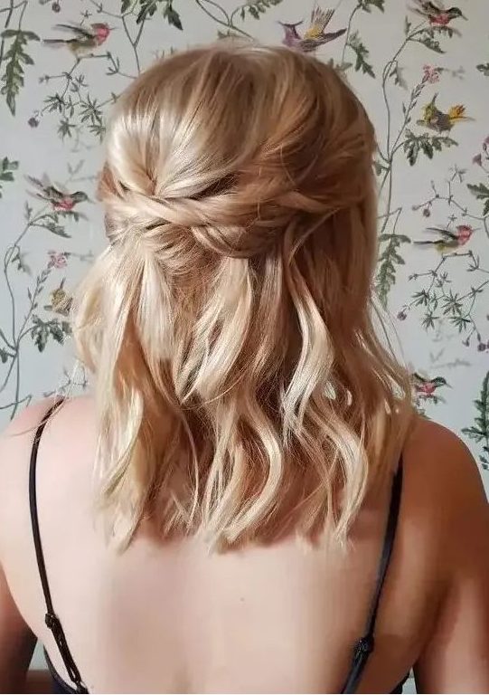 a delicate and relaxed blonde medium half updo with a bump on top, twists and waves down is cool
