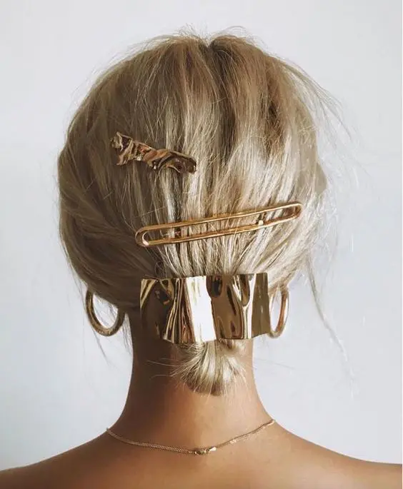 a glam low updo done with gold hair accessories, barrettes and a hair pin is amazing
