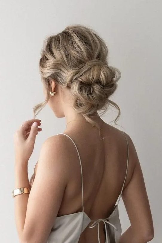 a gorgeous messy woven low bun with a wavy top, some hair down and face-framing locks is a chic solution for a party look