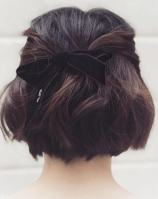 a half updo with twisted touches, a lot of volume and waves, a black velvet ribbon bow is a cool idea