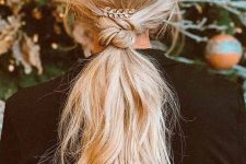 a long low ponytail with a twisted touch, messy wavy hair and a rhinestone feather as an accessory to the hairstyle