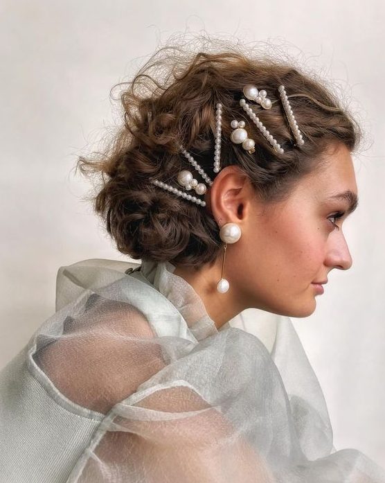 a lovely wavy half updo with multiple pearl bobby pins and statement pearl earrings is wow