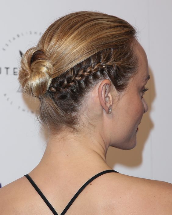 a low ballerina bun with a sleek top and a braid on the side is a cool and catchy hairstyle to rock