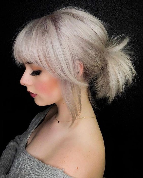 a low bleached blonde ponytail with a bump on top and classic and side bangs is a super cool idea