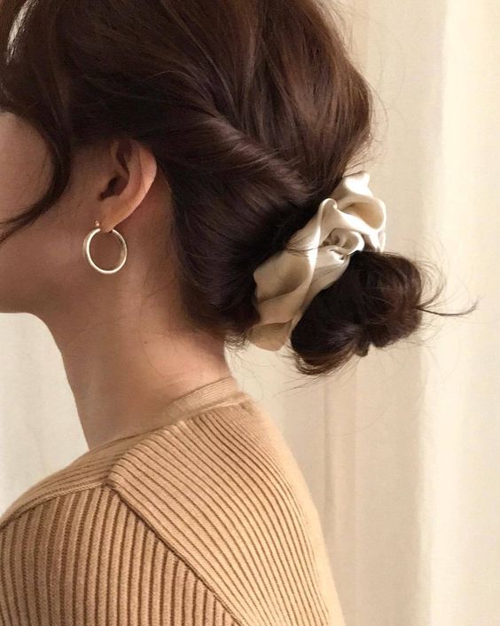 A low bun with twisted hair and face framing bangs plus a scrunchie is a cool hairstyle for Christmas
