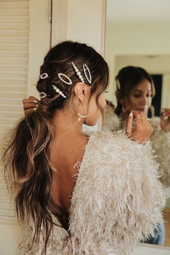 a messy and wavy low ponytail with a messy top and face-framing hair, with pearl bobby pins is super cool