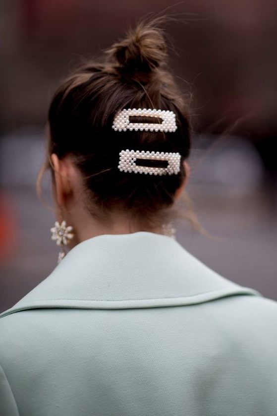 a messy bun accented with pearl hair clips and statement pearl earrings for an ultimate look