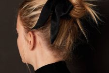 a messy top knot with a messy top and a black ribbon bow on the side is a super chic and catchy idea