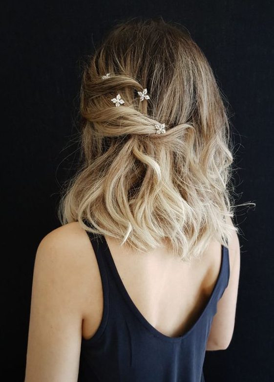 a pretty medium hair half updo with some waves on one side being held by rhinestone hair pieces