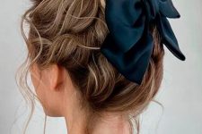 a pretty messy and wavy top knot with a wavy top, some locks down and a black bow for an accent