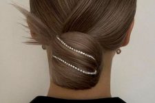 a refined and classy sleek lwo bun accented with rhinestones and with a sleek top is a chic and catchy idea