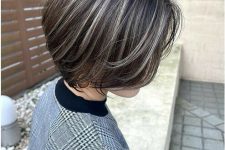 a short brown bob with grey highlights and plenty of volume is a cool way to naturally blend your greys into your dark hair