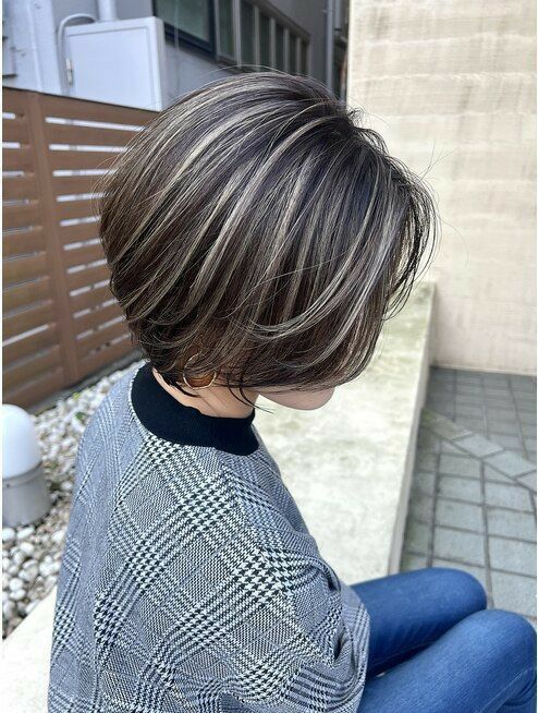 a short brown bob with grey highlights and plenty of volume is a cool way to naturally blend your greys into your dark hair