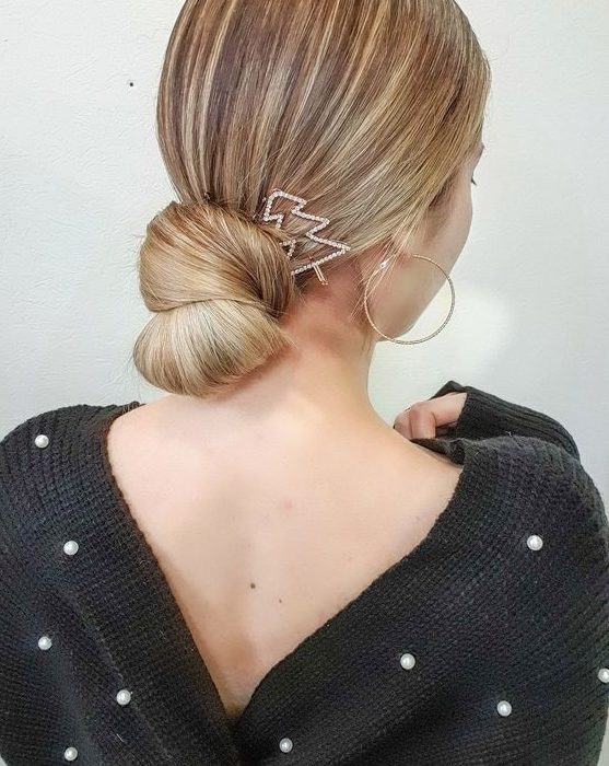 a sleek knotted low bun with a sleek top and a tree-shaped hair pin are a gorgeous combo for a Christmas party