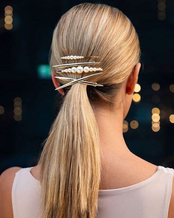 a sleek low ponytail secured with several bobby pins and a barrette for a modern look