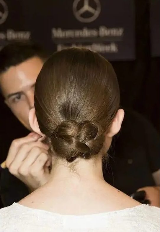 a sleek low updo with a braided bun is a cool and modern interpretation of a traditional low bun or chignon