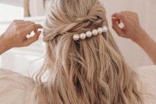 a twisted half updo and a large pearl hair barrette for a modern and fresh look with a touch of feminine