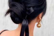an elegant and chic low bun with a volume on top, a black ribbon bow is a very sophisticated hairstyle