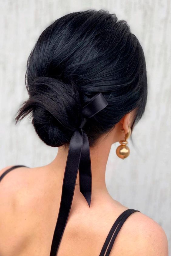 an elegant and chic low bun with a volume on top, a black ribbon bow is a very sophisticated hairstyle