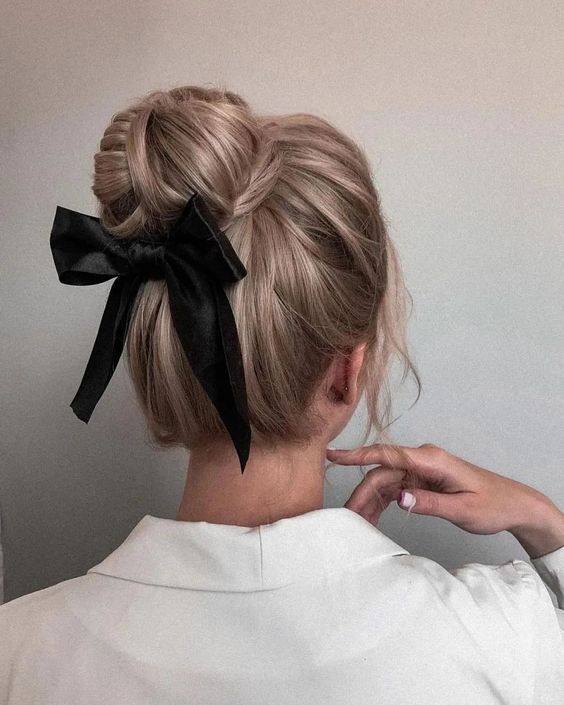 an elegant top knot with some volume on top and a black ribbon bow is a chic and catchy idea for the holidays