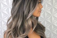 long and volumetric black wavy hair with grey highlights and ombre is a beautiful solution to go if you like your natural greys