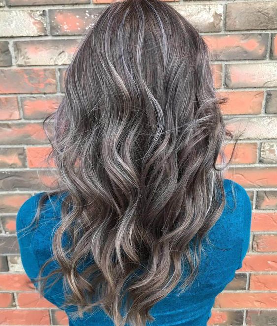 long brown hair with grey accents and waves looks very pretty, cool and chic and naturally grey hair is blended in