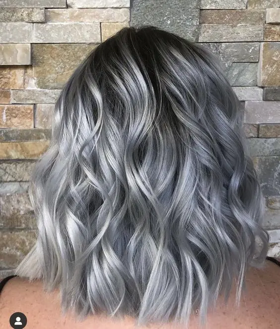 Medium length black hair with a lot of silver grey accents and waves looks amazing and very chic