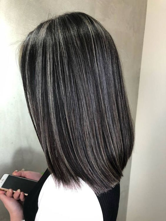 Medium length black hair with silver balayage and a lot of volume is a super chic and eye catchy idea