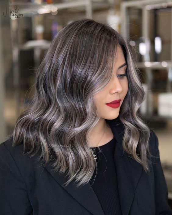 medium-length black wavy hair with beautiful and shiny grey hair blended in and a grey money piece is amazing
