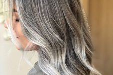 medium-length dark hair accented with silver greys and with matching money piece, with waves, is a lovely idea to transition to grey